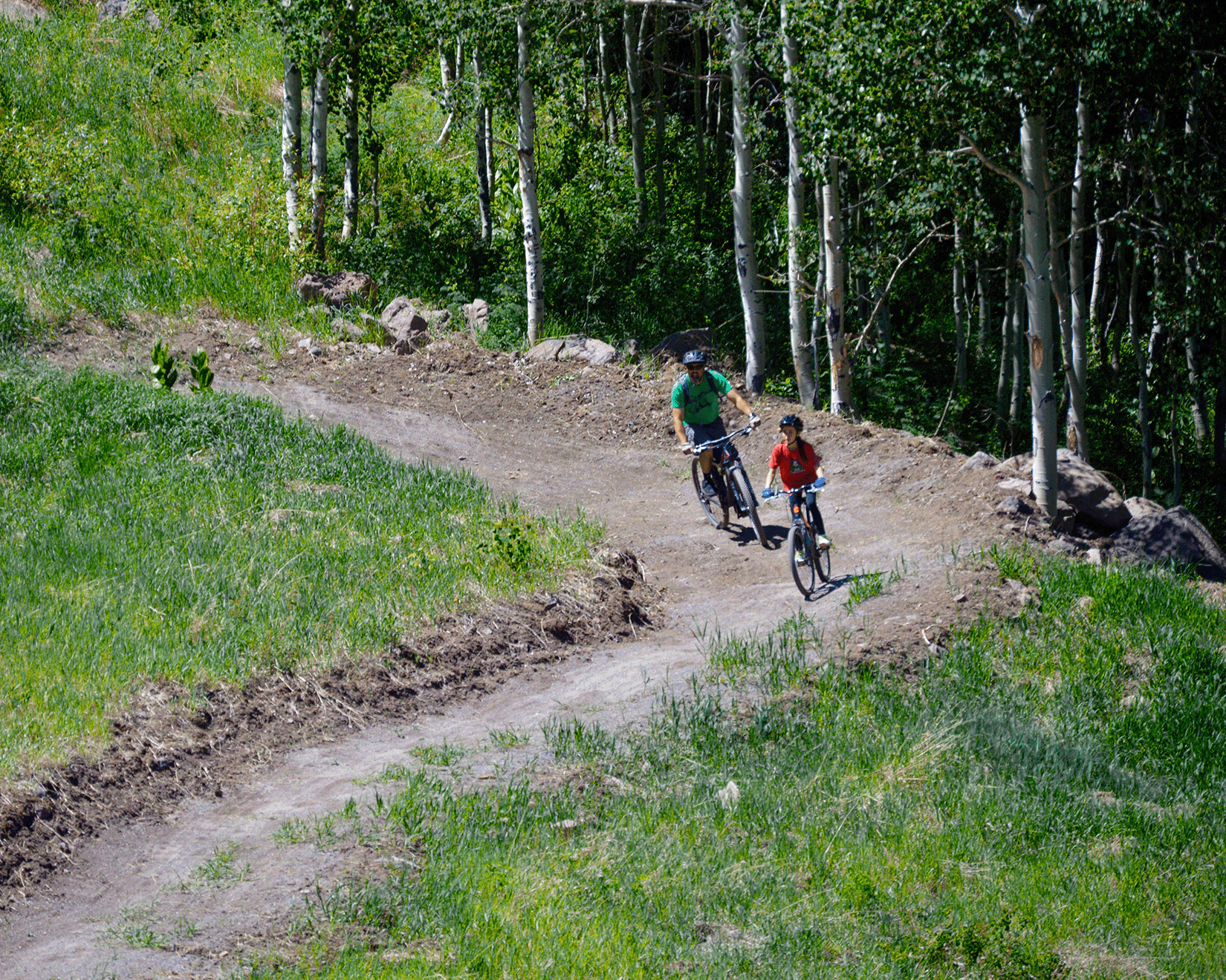 young bike rider with adult following